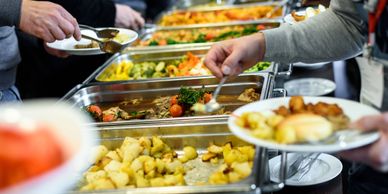 People serving themselves food from a buffet with various dishes.