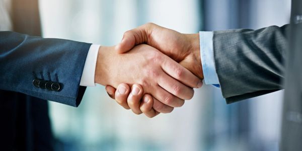 Two people shaking hands in a business setting.