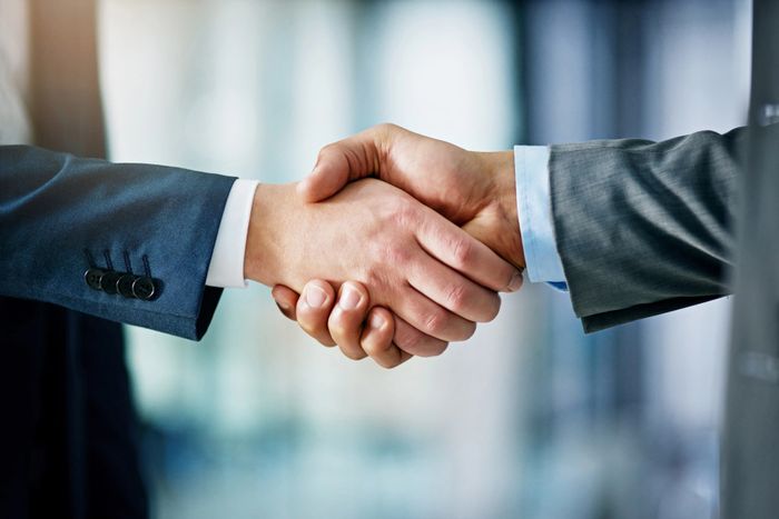 Two businessmen shaking hands in a professional setting.