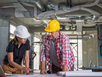 Two construction workers discussing plans at a building site.
