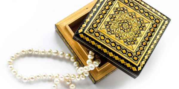 Ornate wooden box with a pearl necklace spilling out.