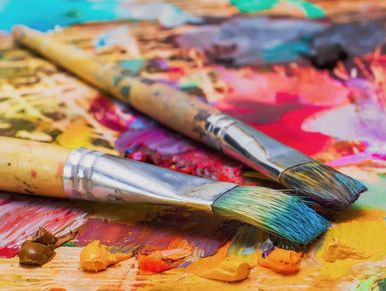 Two paintbrushes on a colorful palette.