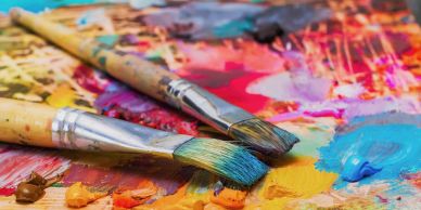 Two paintbrushes on a colorful palette.