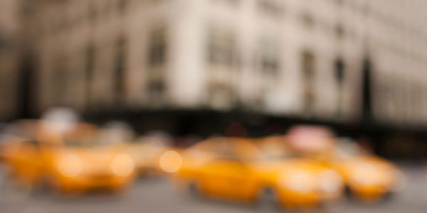 Blurred image of yellow taxis on a city street.