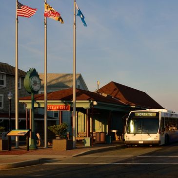 Street with flags and a trolley stop at sunset.