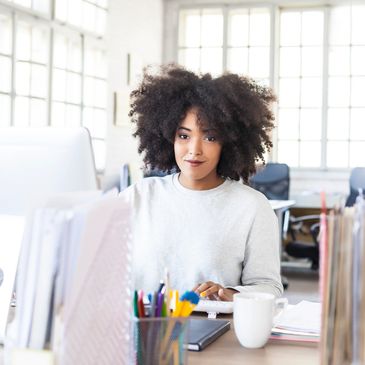 Young woman working at a desk in a bright office space.