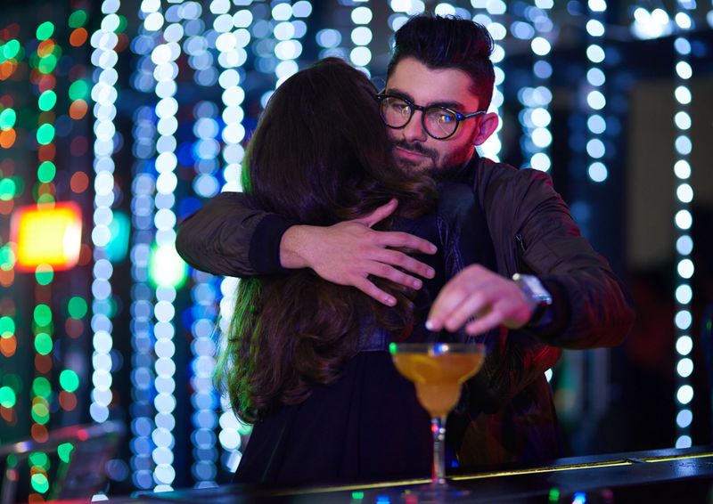 Shot of a man dropping a pill into a  woman's cocktail behind her back in a nightclub