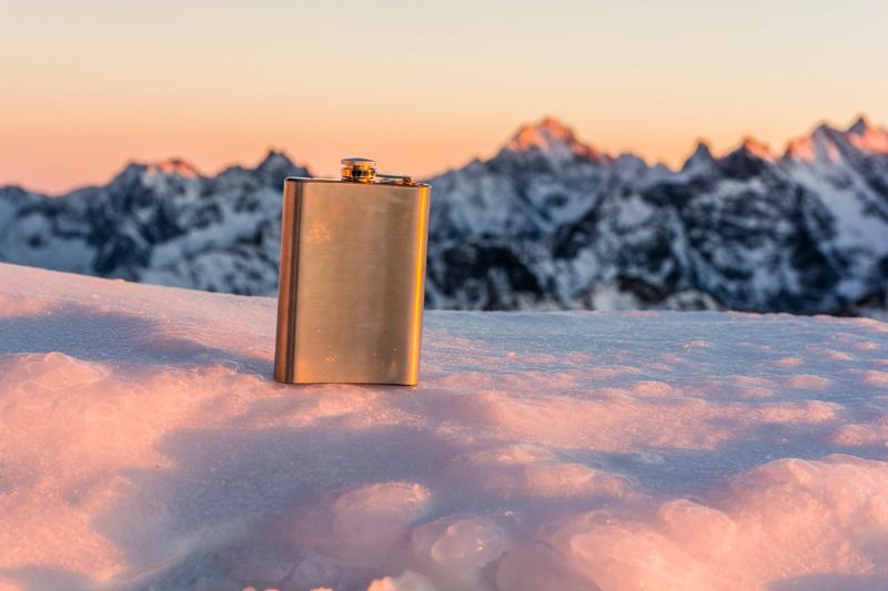Hip flask on a background of mountains at sunset.