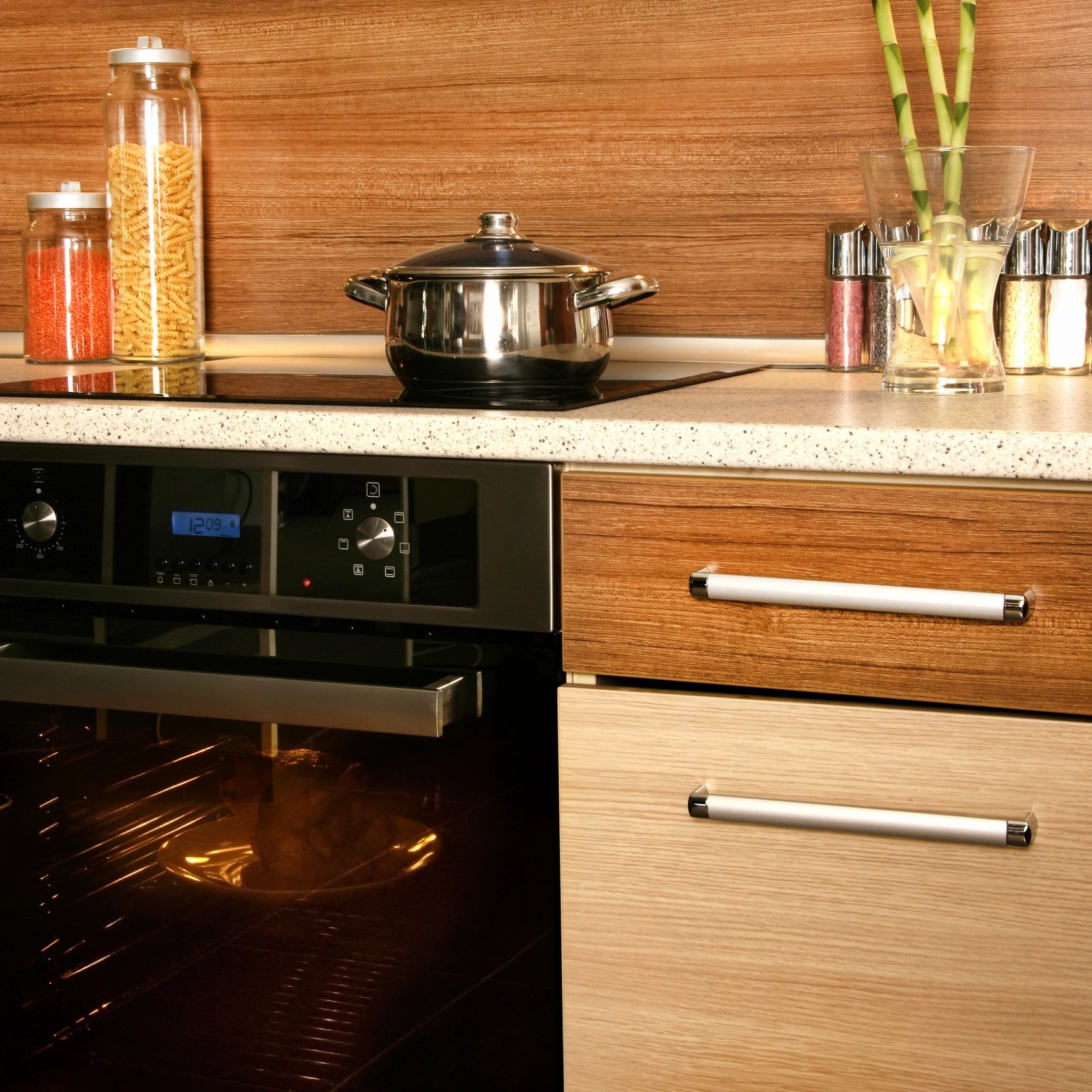 Modern kitchen countertop with a pot, jars, and bamboo in a glass.