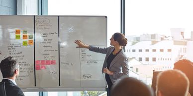Woman presenting ideas on a whiteboard in a meeting.