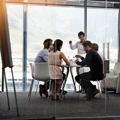 Business team in a meeting room with a woman leading the discussion.