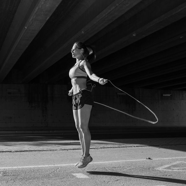 Frau springt Seil unter Brücke, schwarz-weiß.