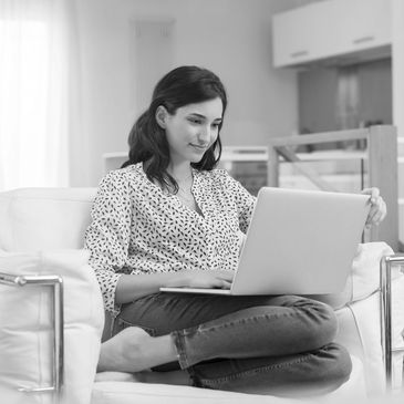 Woman sitting on couch using a laptop.