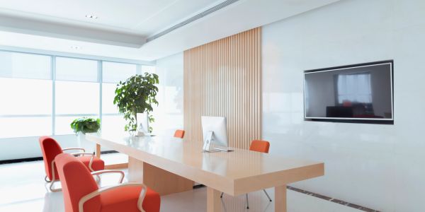 Modern, bright office with orange chairs and plants.