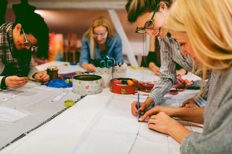 Female students on sewing class. Students practicing to use basic pattern and tailoring. They are focused on their work. Their teacher helping them.