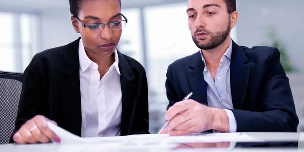Two professionals reviewing documents together in a modern office.