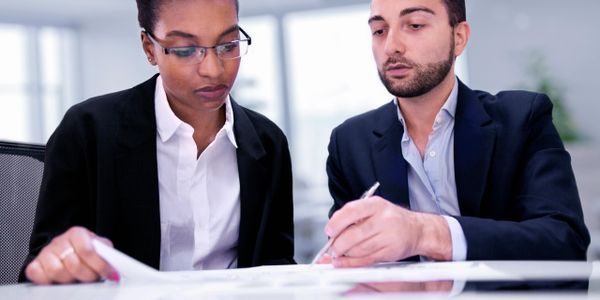 Two professionals reviewing documents together in a modern office.