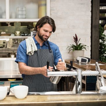 Barista preparing coffee with a cheerful smile in a modern cafe.