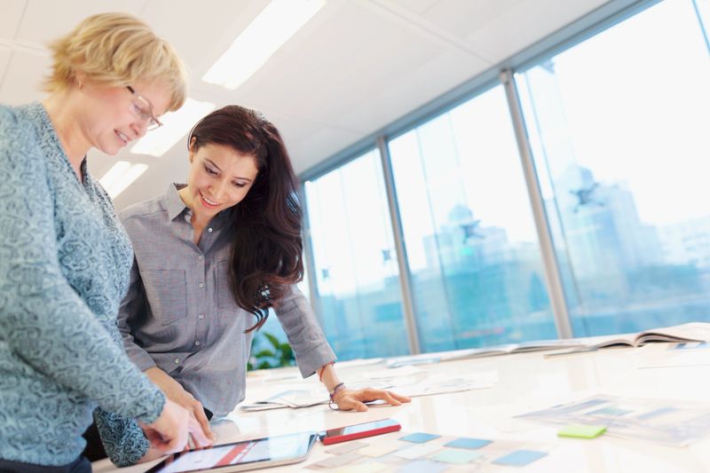 Women reviewing plans on tablet computer in studio