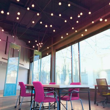 Bright modern office with pink chairs and hanging lights.