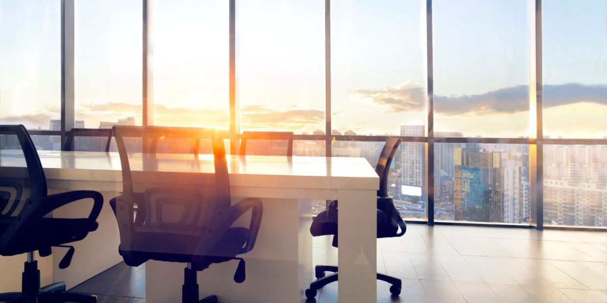 Modern office space with ergonomic chairs and a city view at sunrise.