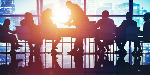Silhouettes of people in a meeting room with city skyline in the background.