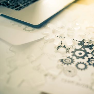 Puzzle pieces with gear designs under a laptop keyboard.