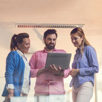Three colleagues discussing work while looking at a laptop.