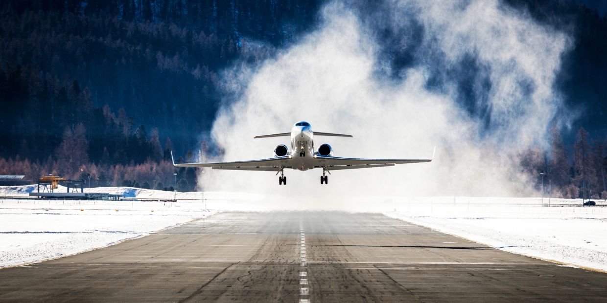 Private jet taking off from a snowy runway with a smoky background.