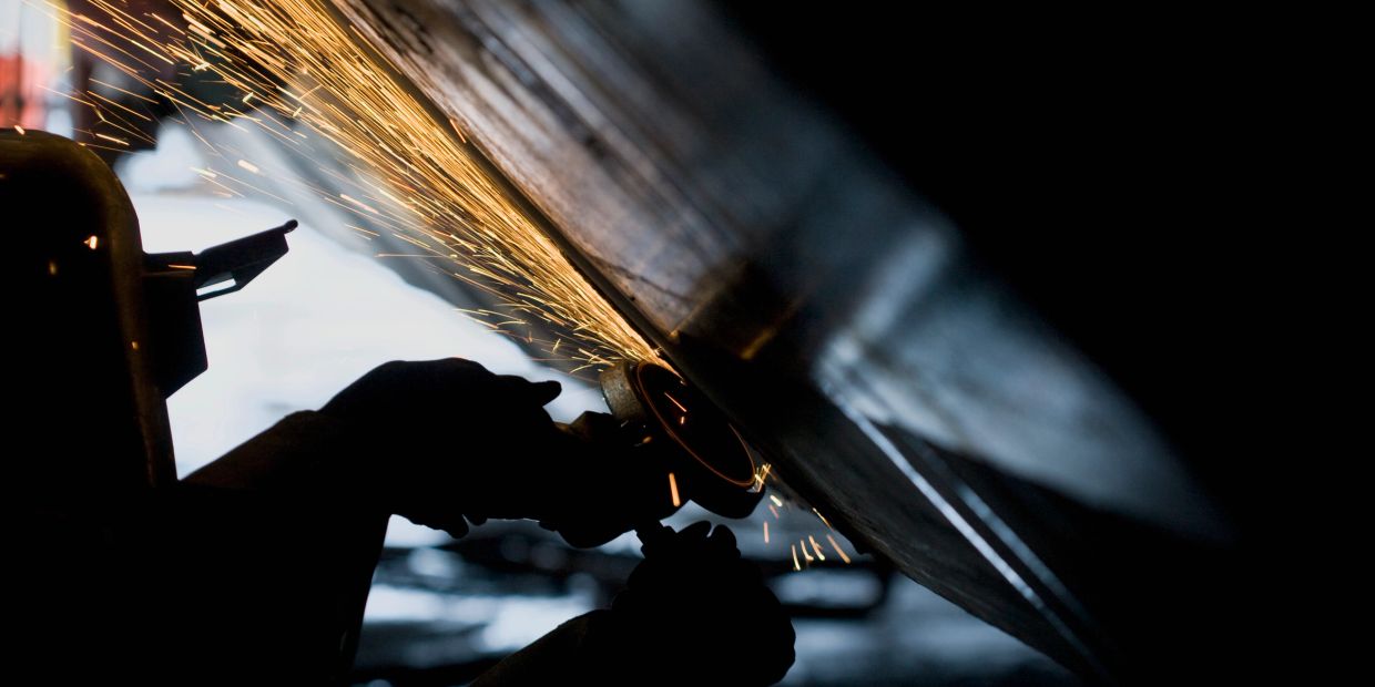 Worker grinding metal, creating sparks.