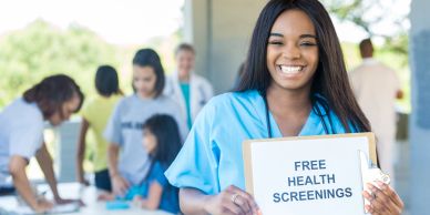 Smiling nurse holding a sign for free health screenings.