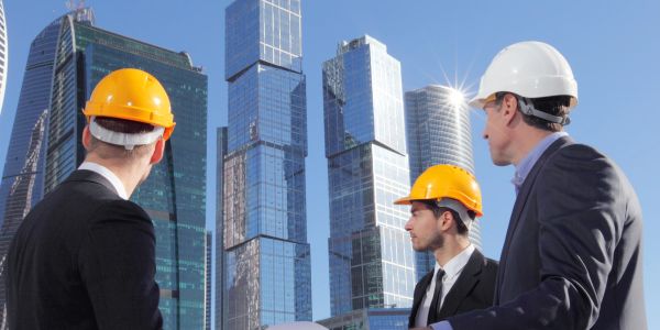Engineers examining construction site with skyscrapers.