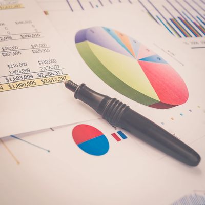 Financial documents with pie charts and a pen highlighting figures.