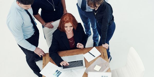 Business team collaborating around a laptop in a bright office.