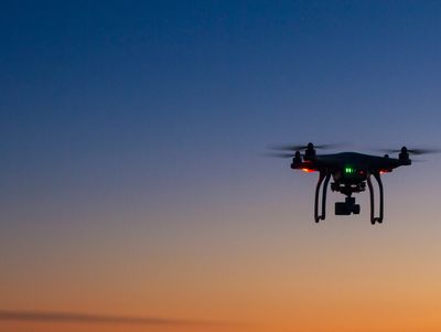 Drone flying at sunset with colorful sky.