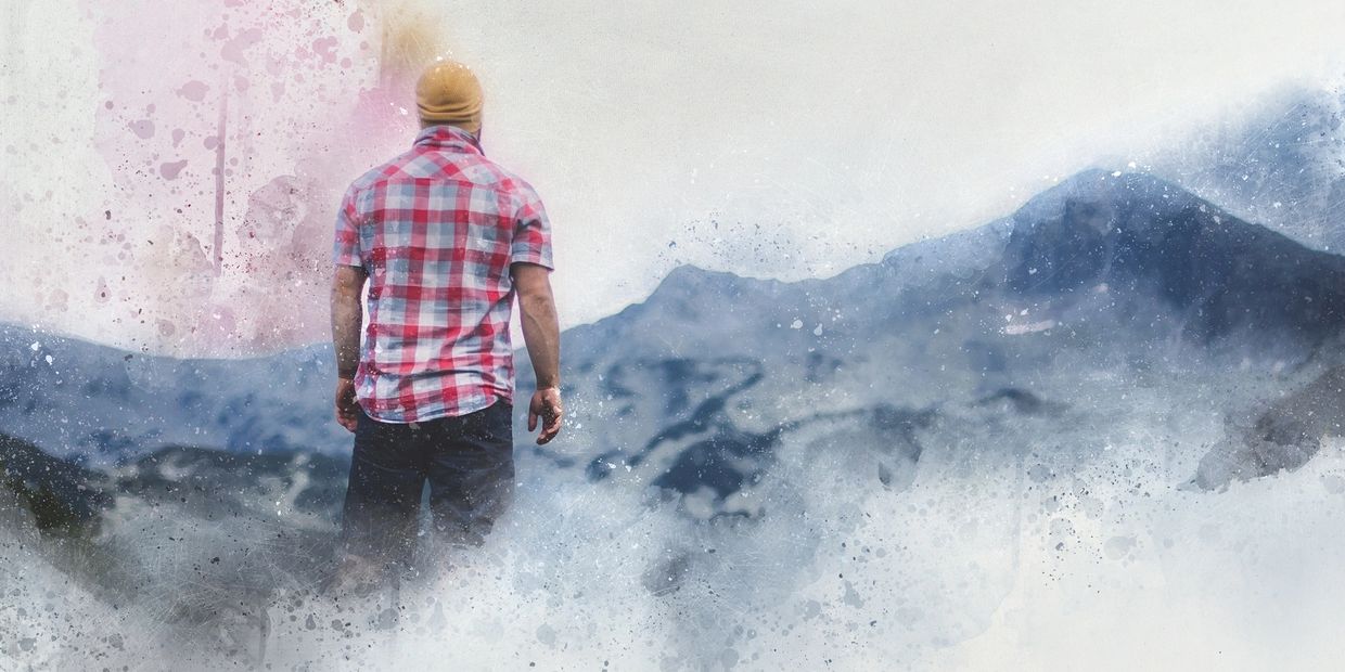 A man in a red plaid shirt stands amidst misty mountains with an artistic splash effect.