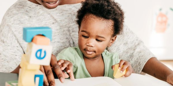 Child playing with blocks and reading with an adult.