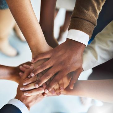 Hands stacked together symbolizing teamwork and unity.