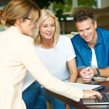 Three people discussing something on a laptop.
