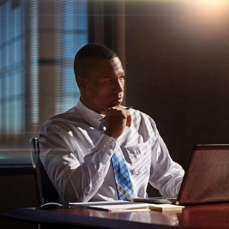 Shot of a young man contemplating while using his laptop