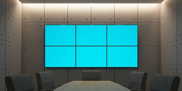 Modern conference room with six large blue digital screens and dark chairs.