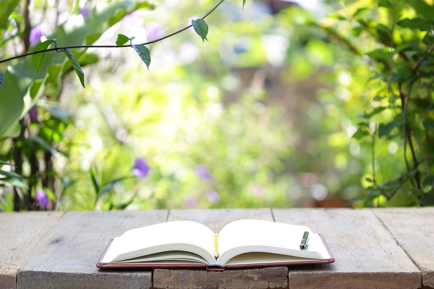 Open Christian gratitude journal on wooden table with pen and peaceful garden background 