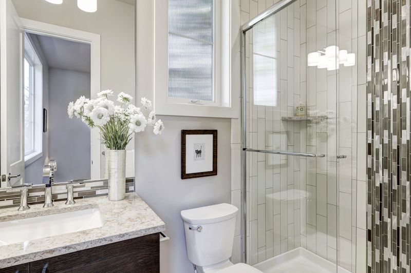 Glass walk-in shower with white subway tiled surround accented with vertical mosaic tile strip in new luxury home bathroom. Northwest, USA