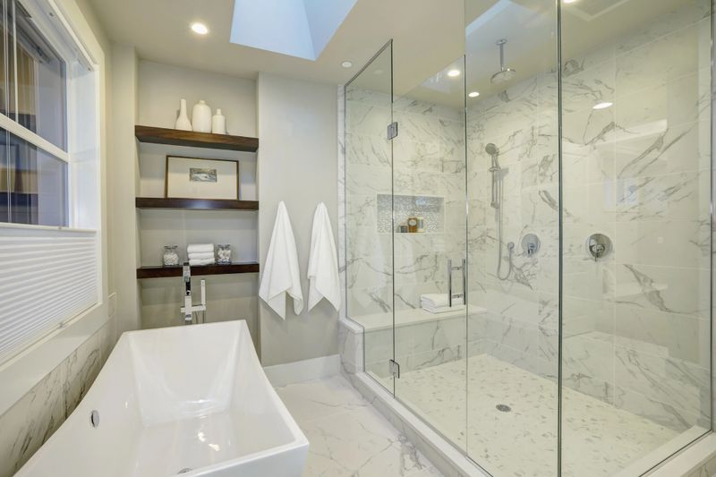 Amazing white and gray marble master bathroom with large glass walk-in shower, freestanding tub and skylights on the ceiling. Northwest, USA