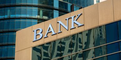 Modern bank building with reflective glass and large BANK sign.