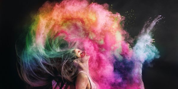 Woman flipping hair with colorful powder explosion.