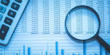 Magnifying glass focusing on financial data with calculator nearby.