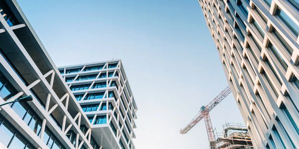 Modern office buildings with a construction crane under clear blue sky.