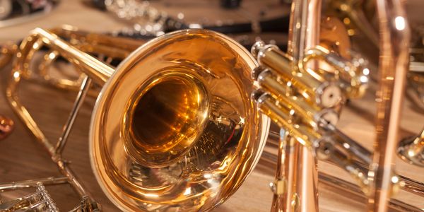 Close-up of brass musical instruments on a wooden surface.