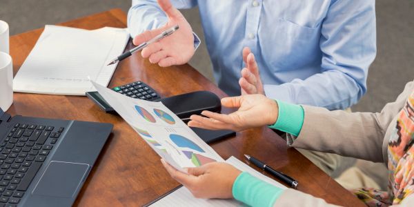 Two people discussing charts and data at a desk.